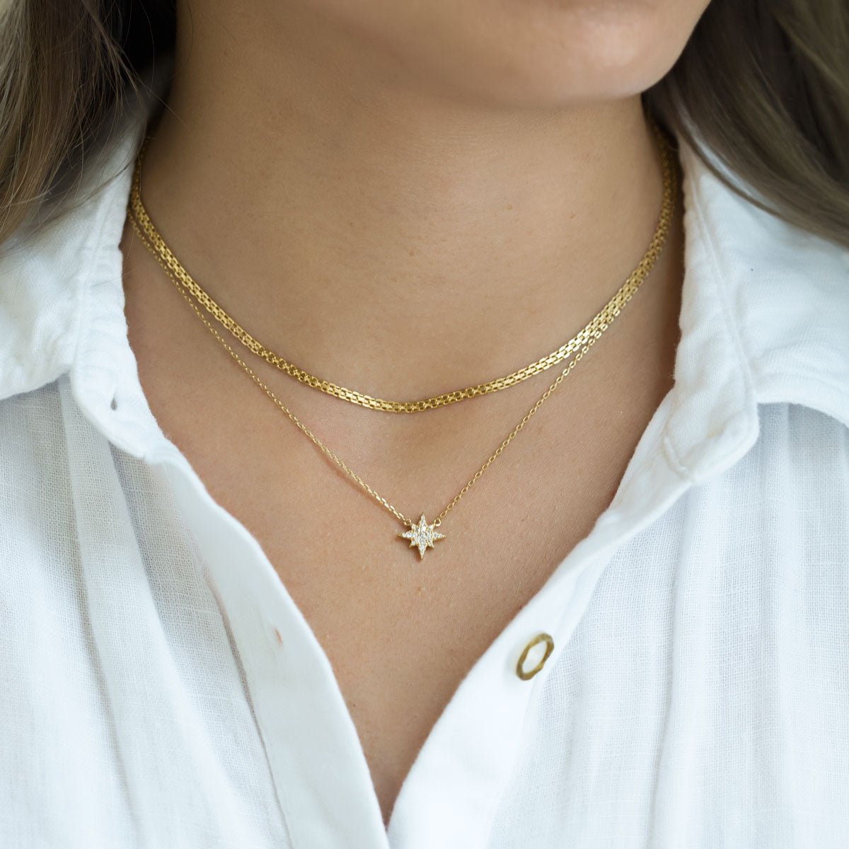 Gold vermeil starburst pendant necklace with a white zirconia pave star, shown on a model's neckline