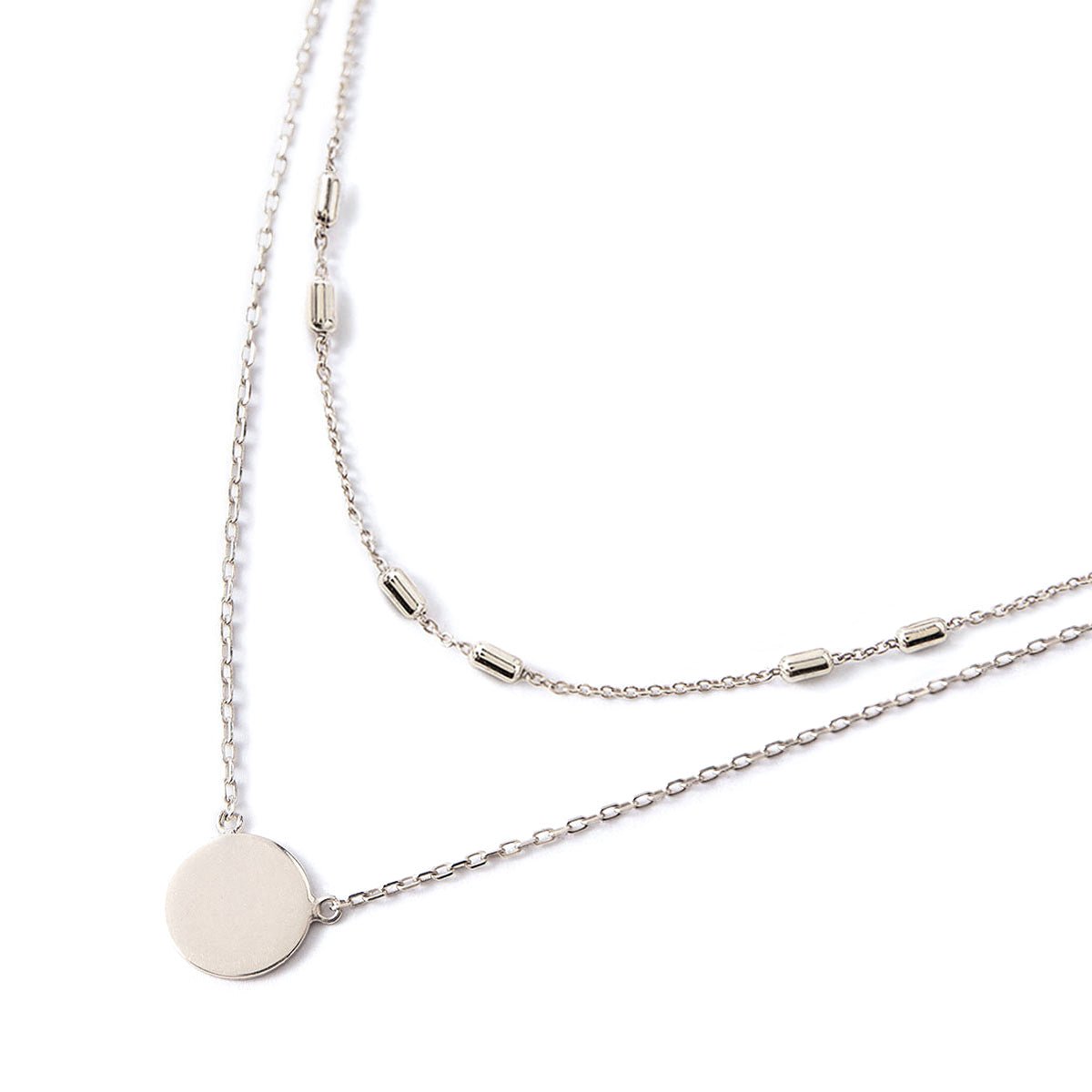 Sterling silver disc pendant necklace layered with a beaded chain, on a white background