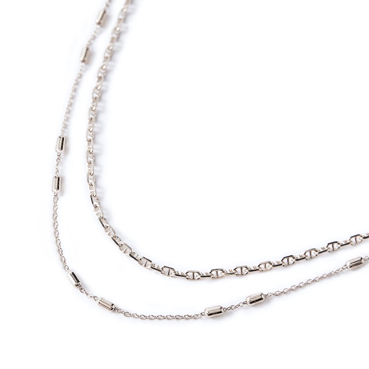 Sterling silver two-strand choker with patterned and beaded station chains, laid on a white background