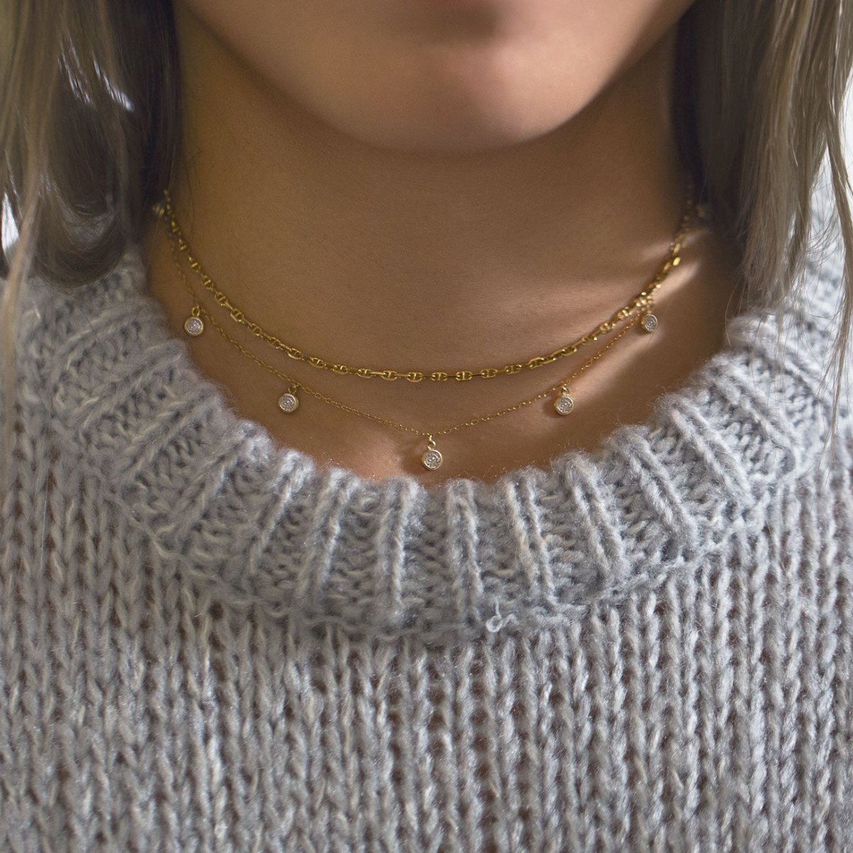 Gold vermeil layered necklace duo with clear crystal drops, shown on a model over a gray sweater