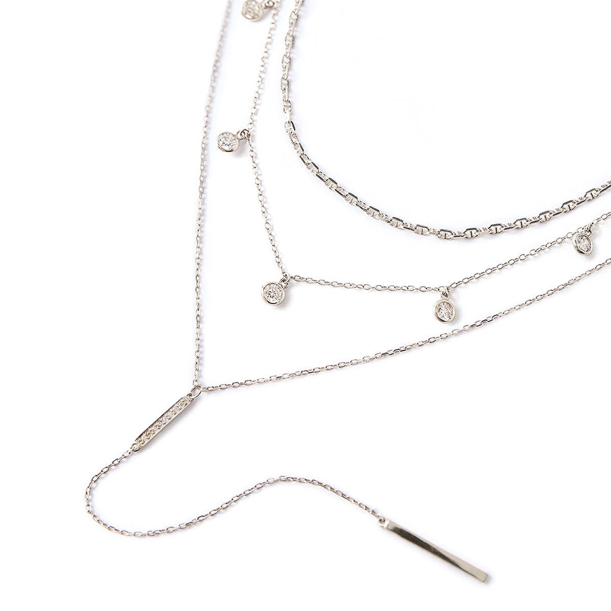 Sterling silver layered necklace trio with bezel-set clear crystal drops and a bar lariat, on a white background