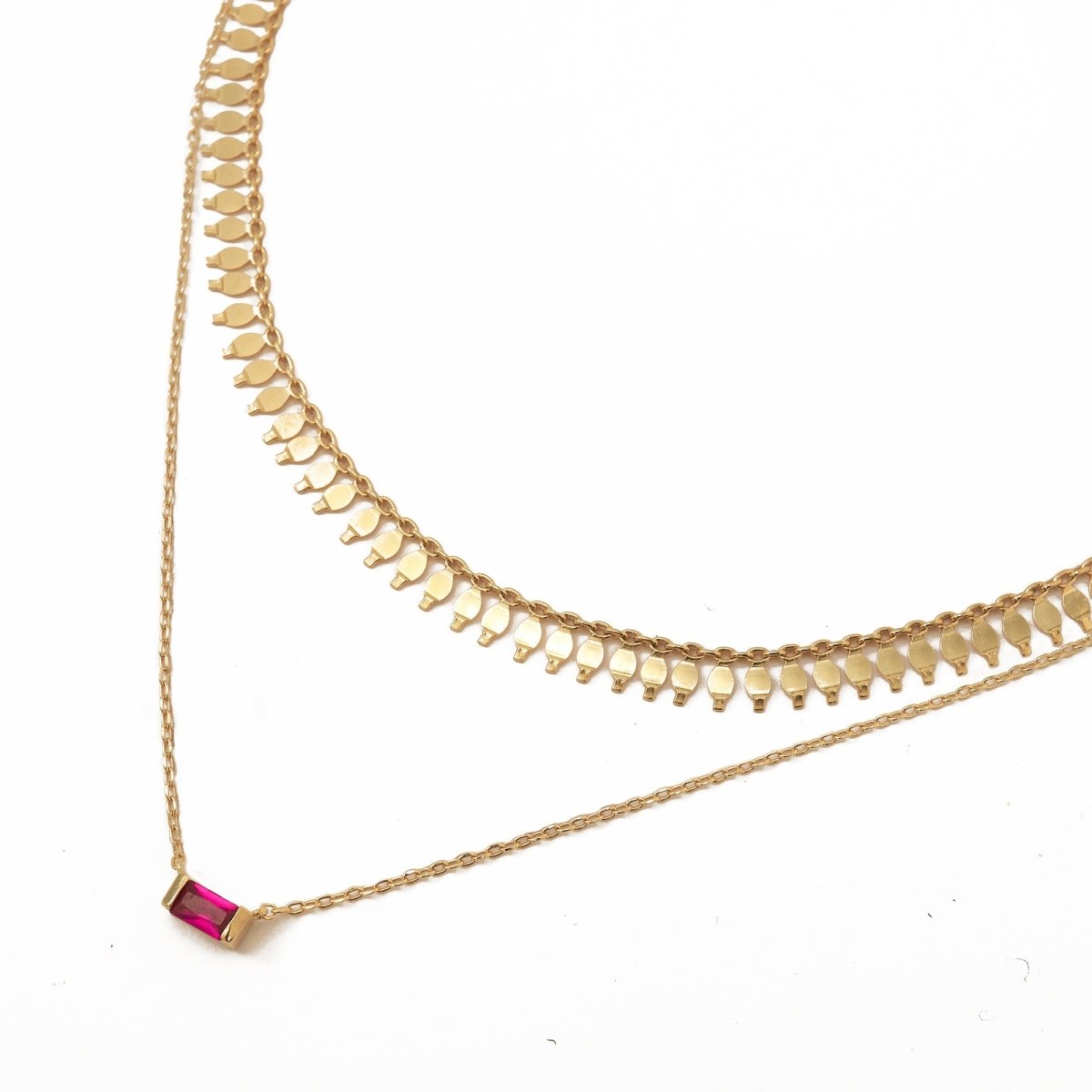 Gold vermeil layered necklaces with a ruby baguette pendant, on a white background