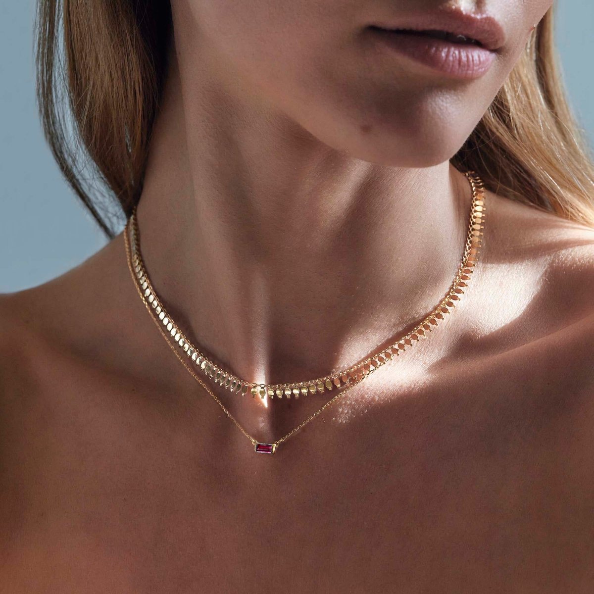 Gold vermeil layered duo with a ruby baguette pendant, shown on a model's neckline