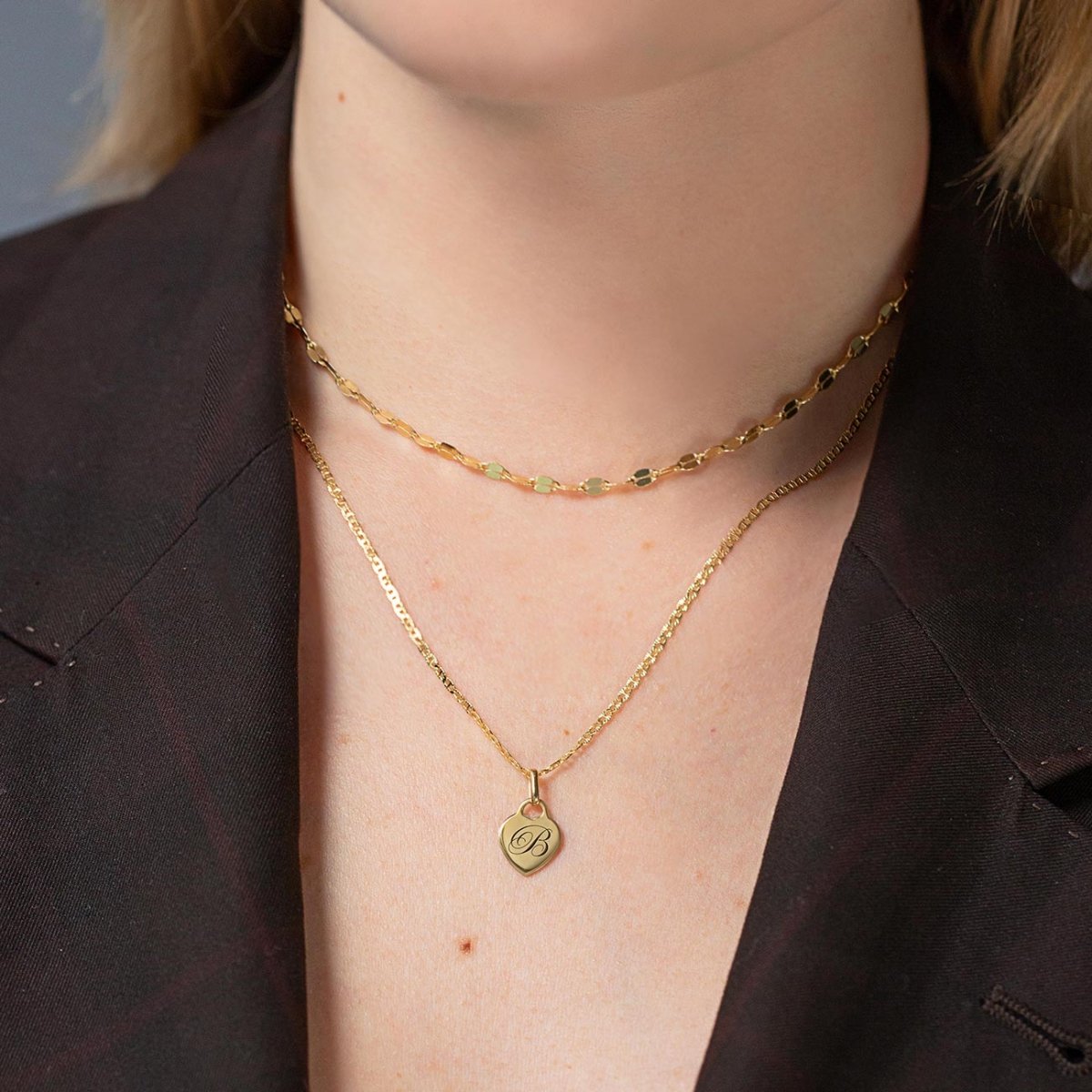Gold vermeil heart charm engraved with an initial on a thin chain, shown on a model's neckline