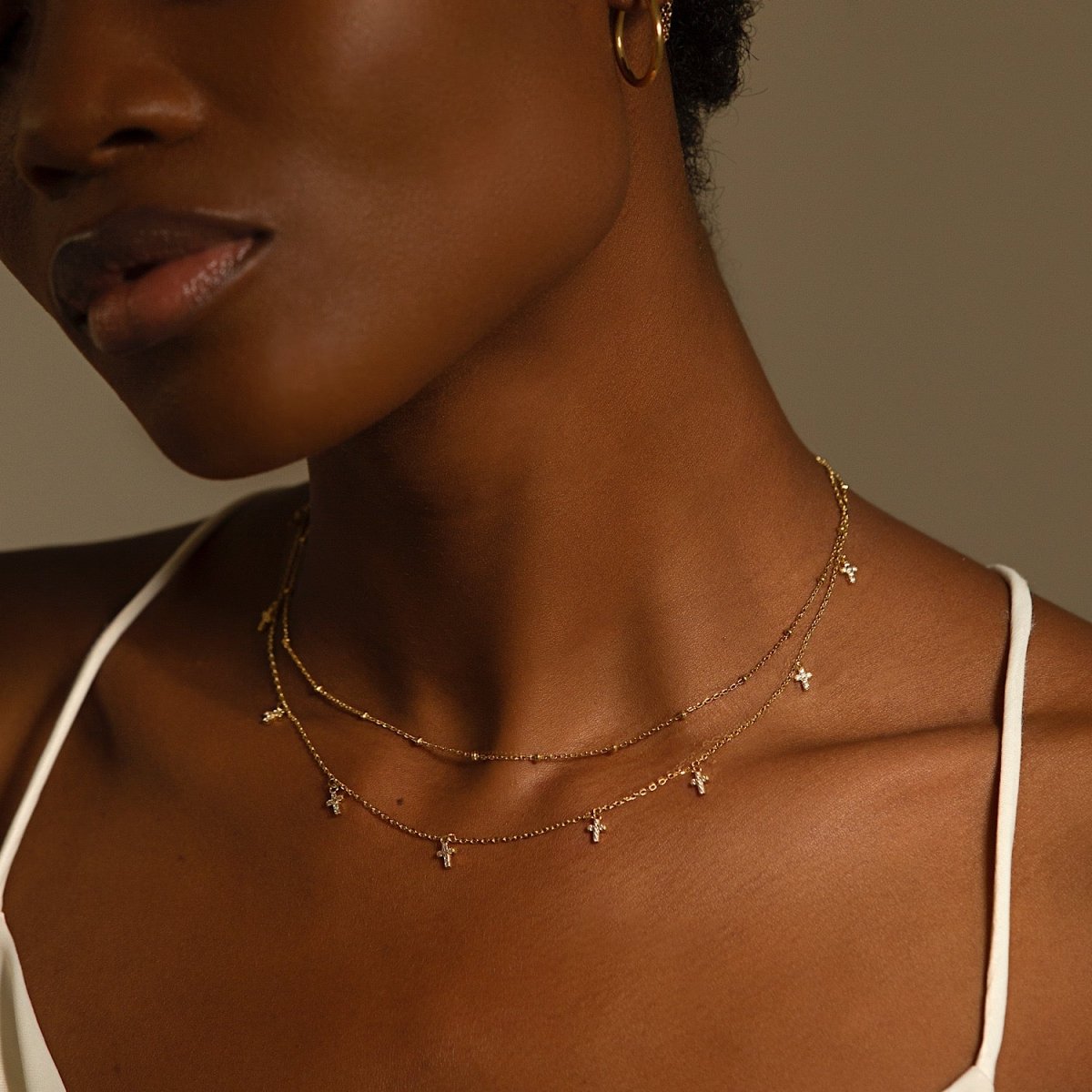 Gold vermeil beaded chain choker layered on a model's neckline with a dangling-charm chain
