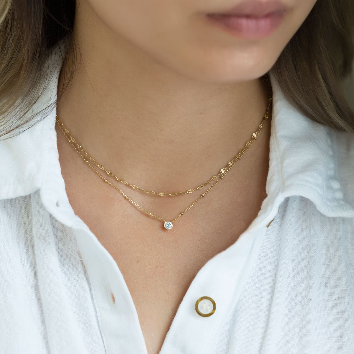 Gold vermeil clear-stone pendant necklace layered with a beaded chain on a model