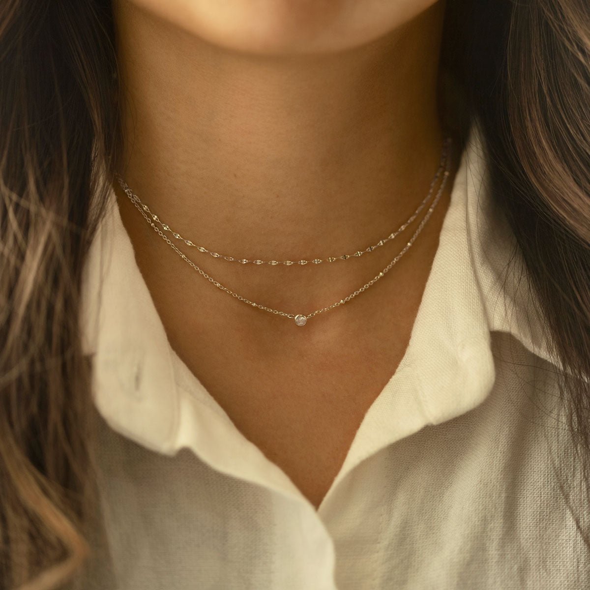 Sterling silver layered choker with a beaded chain and a single round clear stone, shown on a model's neckline