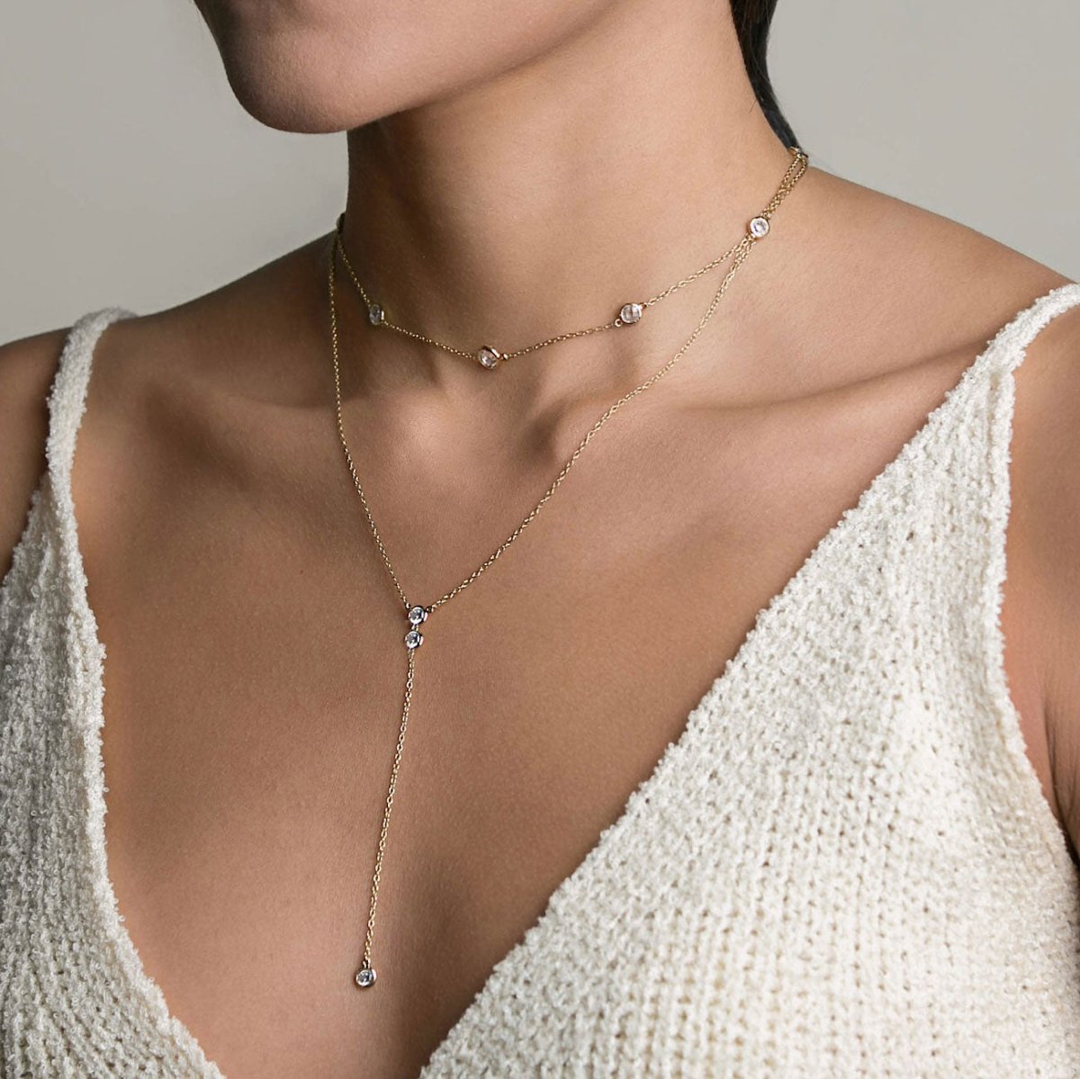 Gold vermeil station choker and Y-drop lariat with white zirconia, shown on a model's neckline