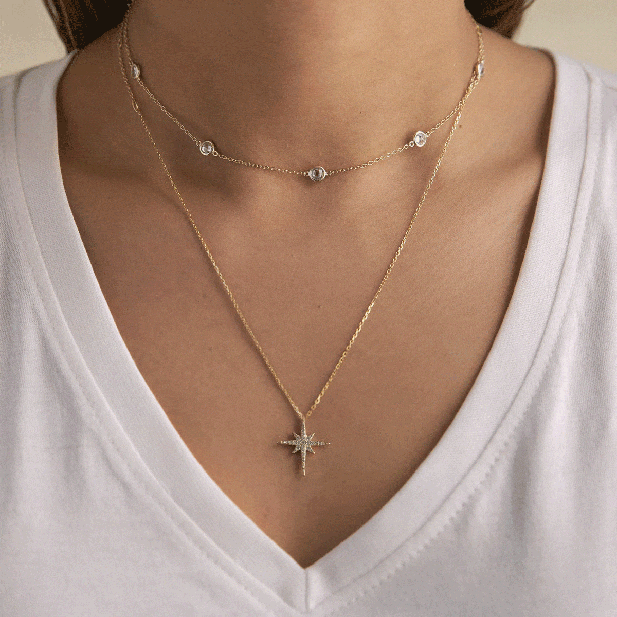 Gold vermeil layered star-pendant necklace duo with clear stones, shown on a model's neckline