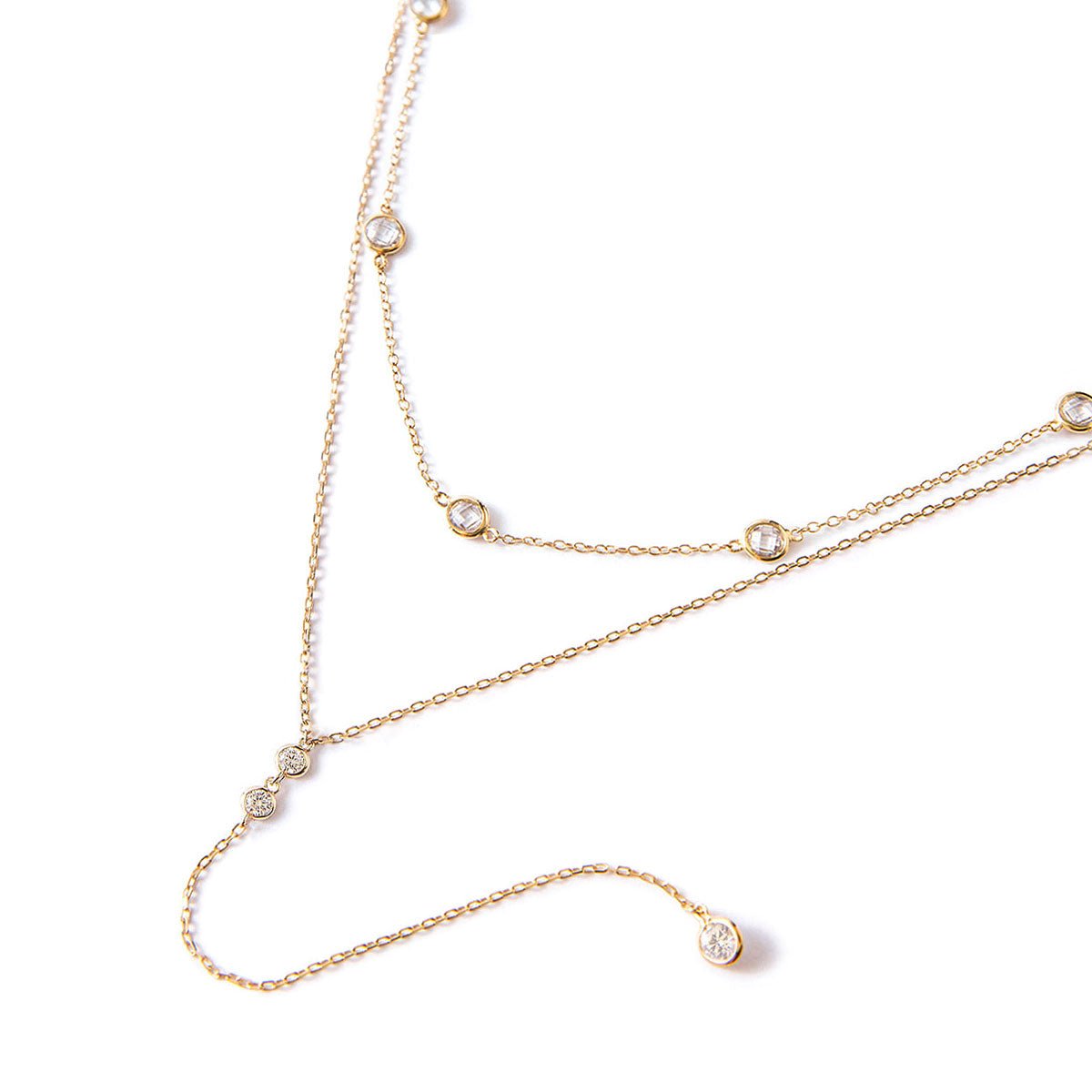 Gold vermeil layered choker and lariat duo with white zirconia stations, laid on a white background