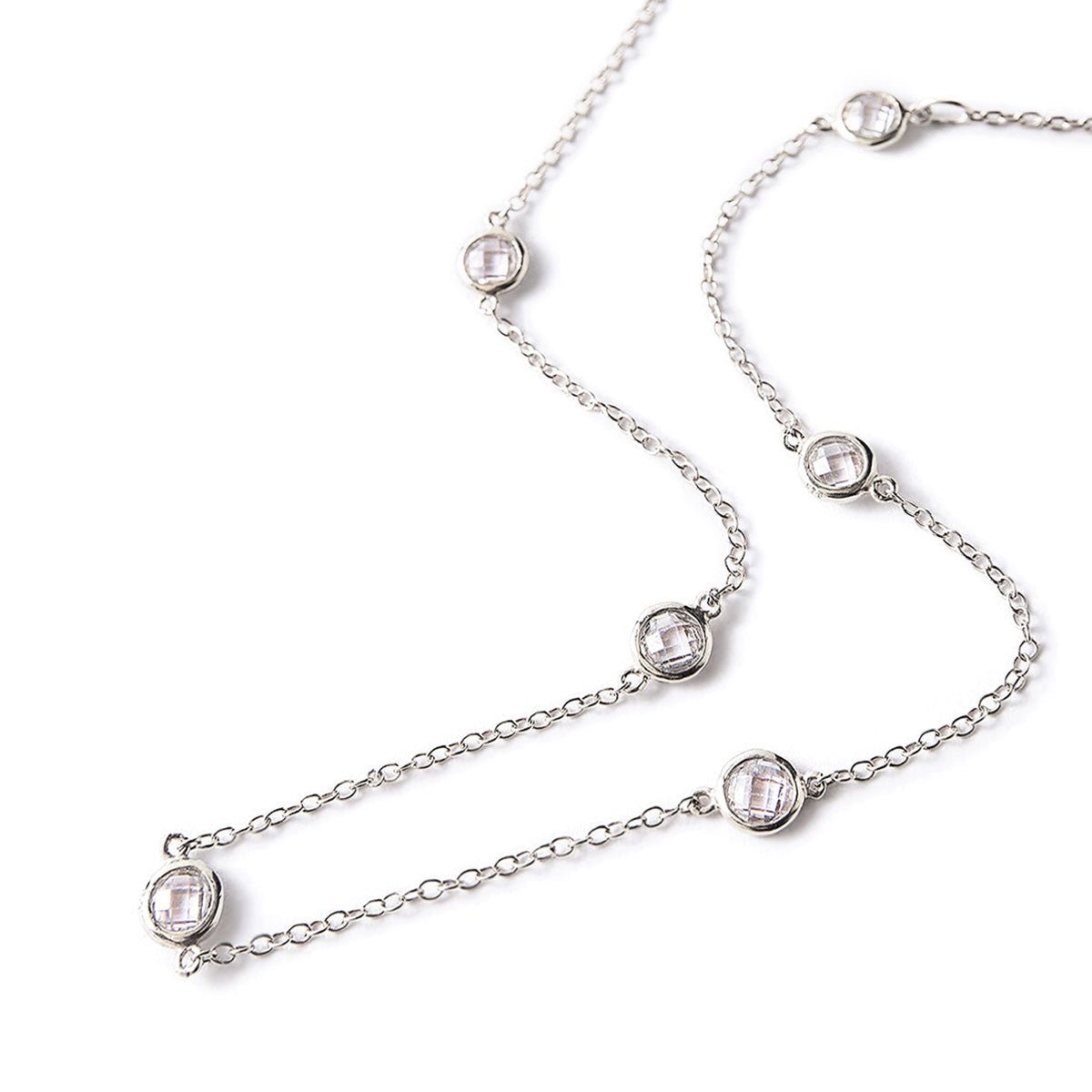 Sterling silver station choker with round clear faceted stones along the chain, laid on a white background
