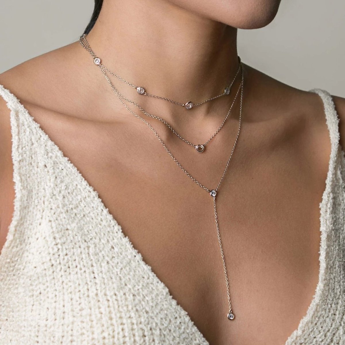 Sterling silver zirconia lariat necklace layered as a trio, shown on a model's neckline