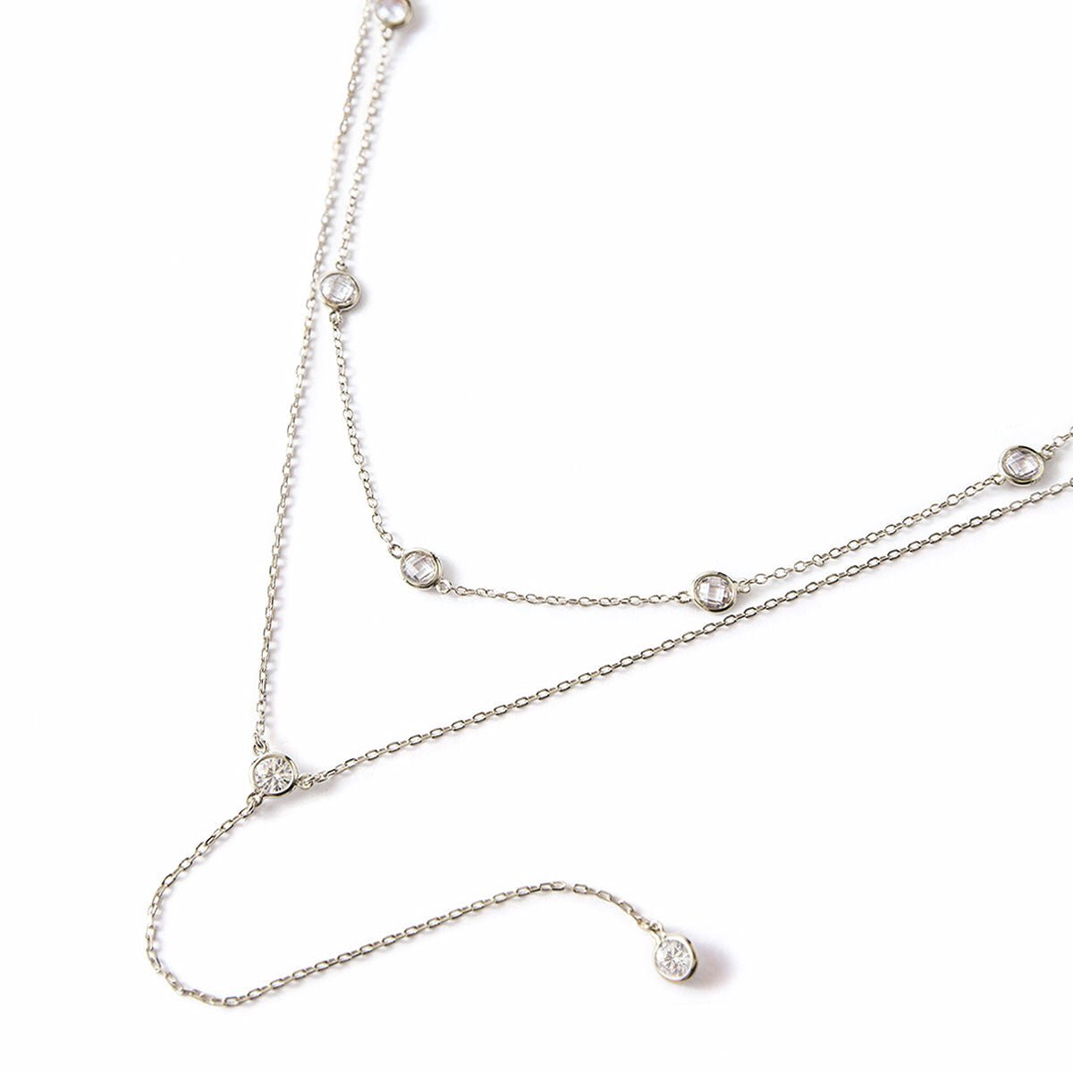 Sterling silver layered lariat and station necklace duo with round clear stones, on a white background