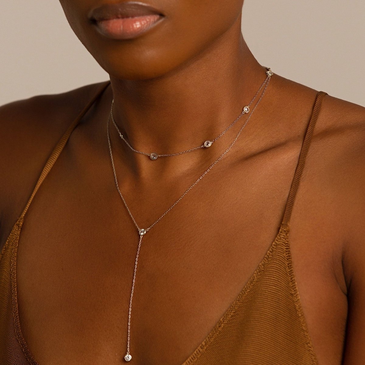 Sterling silver station choker and lariat necklace duo with clear stones, shown on a model's neckline