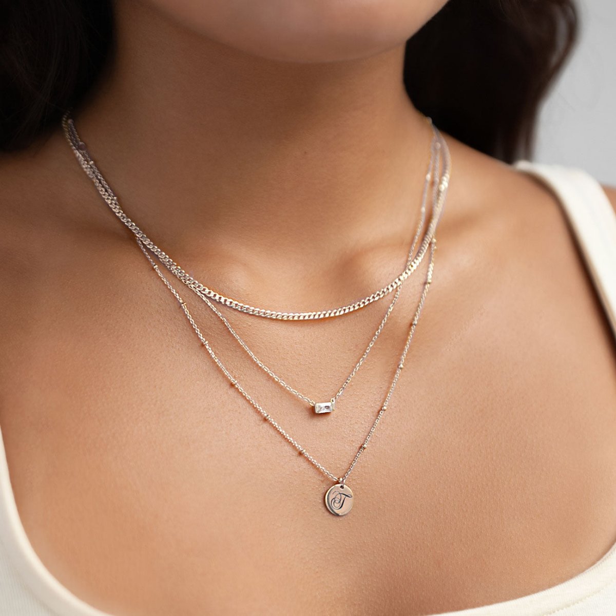 Sterling silver flat Cuban curb chain necklace, shown loose in an S-curve on a white background