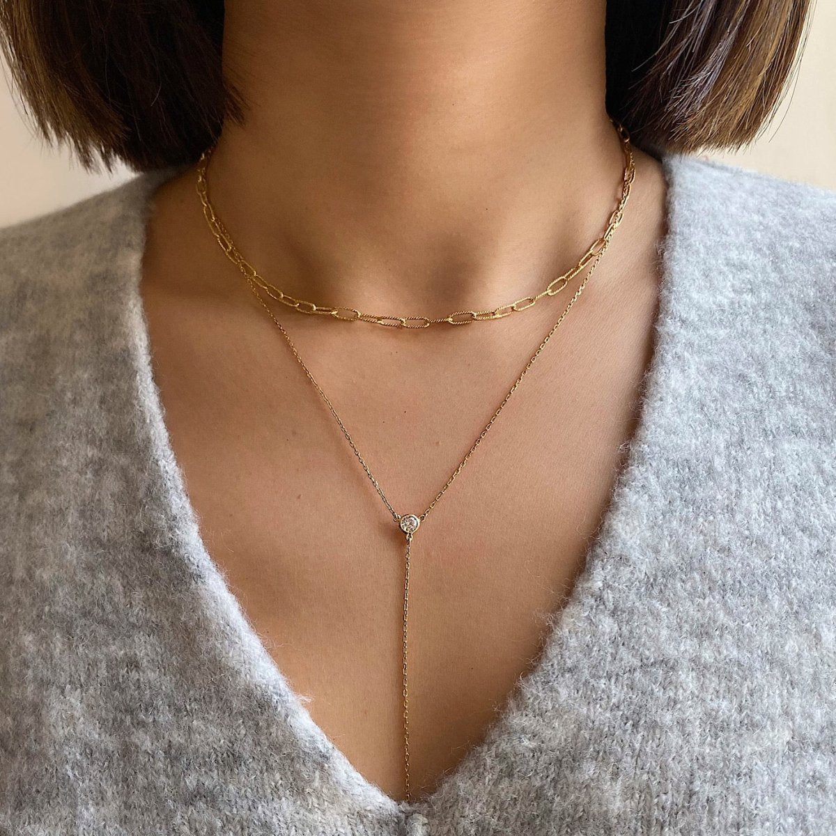 Gold vermeil paperclip chain and Y-lariat with a clear crystal, shown over a grey sweater