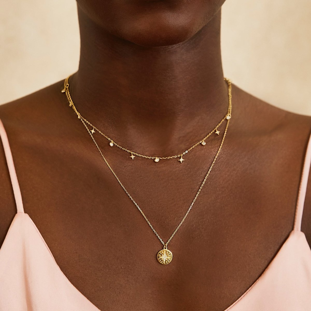 Gold vermeil star dangle necklace with white zirconia charms, shown layered on a model's neckline