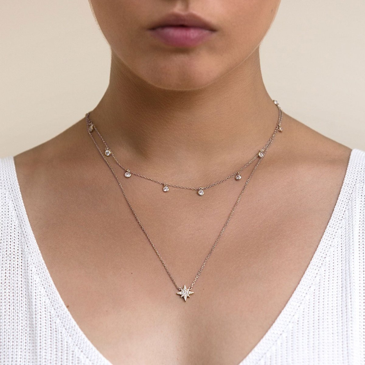Sterling silver layered choker duo with clear stone drops and a starburst pendant, shown on a model's neckline
