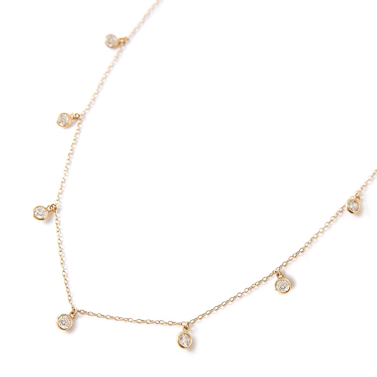 Gold vermeil choker chain with dangling clear bezel stones, laid on a white background