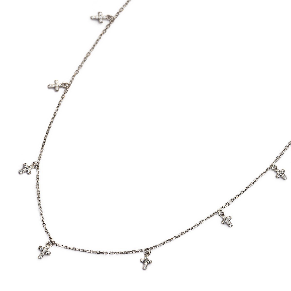 Sterling silver cross dangle necklace with white zirconia crosses, laid on a white background