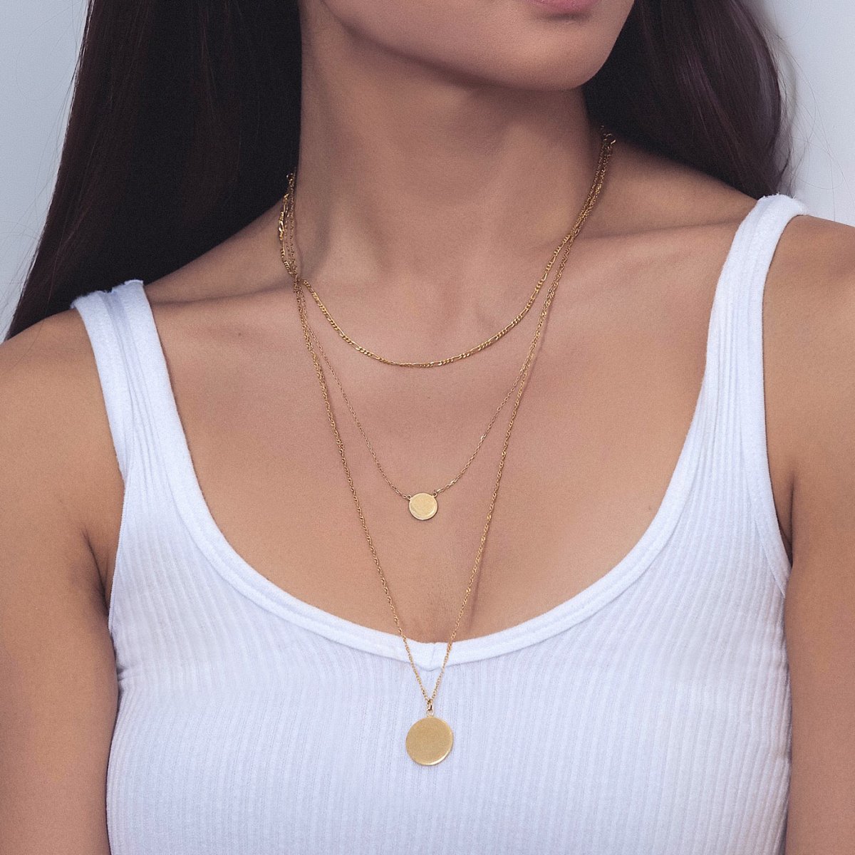 Gold vermeil Figaro disc trio necklace layered with disc pendants, shown on a model's neckline