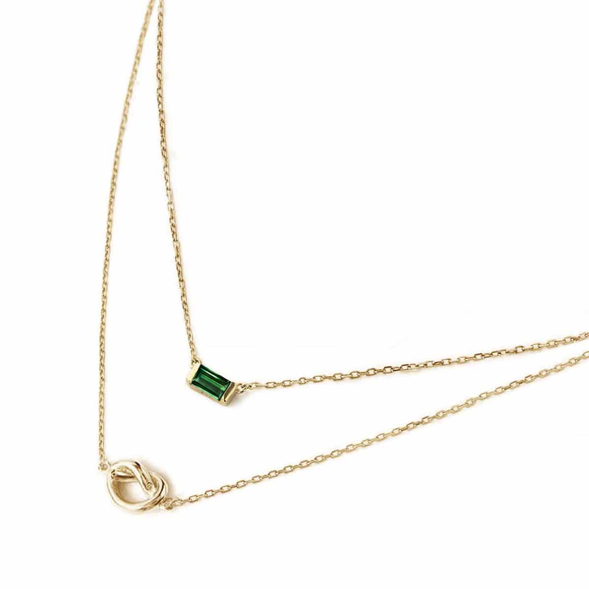 Gold vermeil layered duo necklace with a green baguette emerald and a knot, on a white background