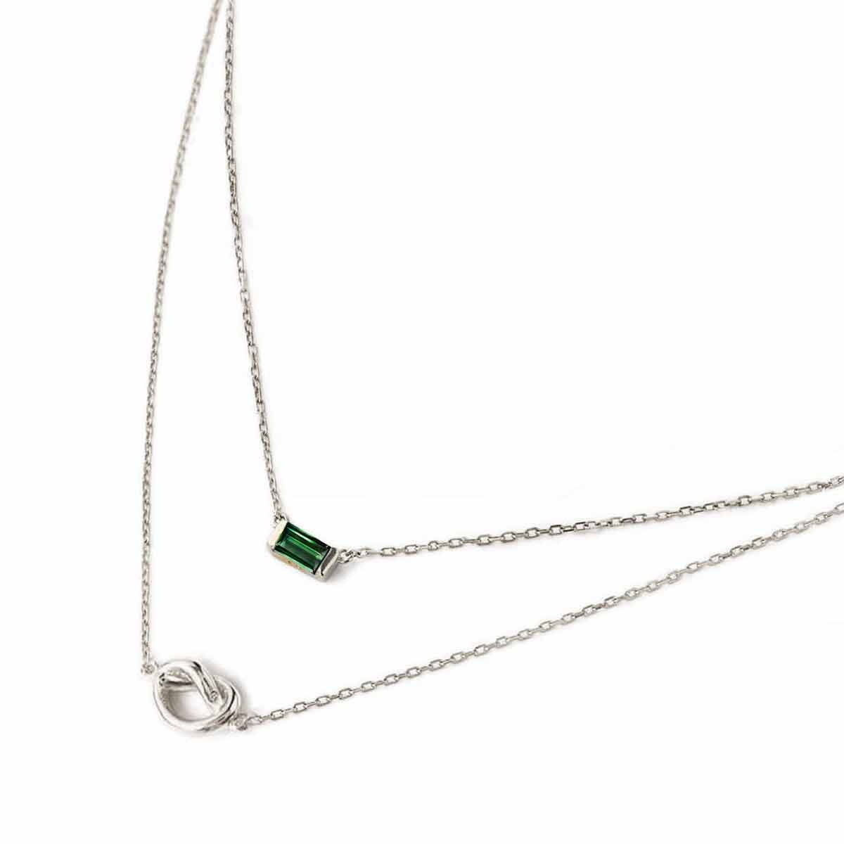 Sterling silver layered duo necklace with a green baguette emerald and a knot, on a white background