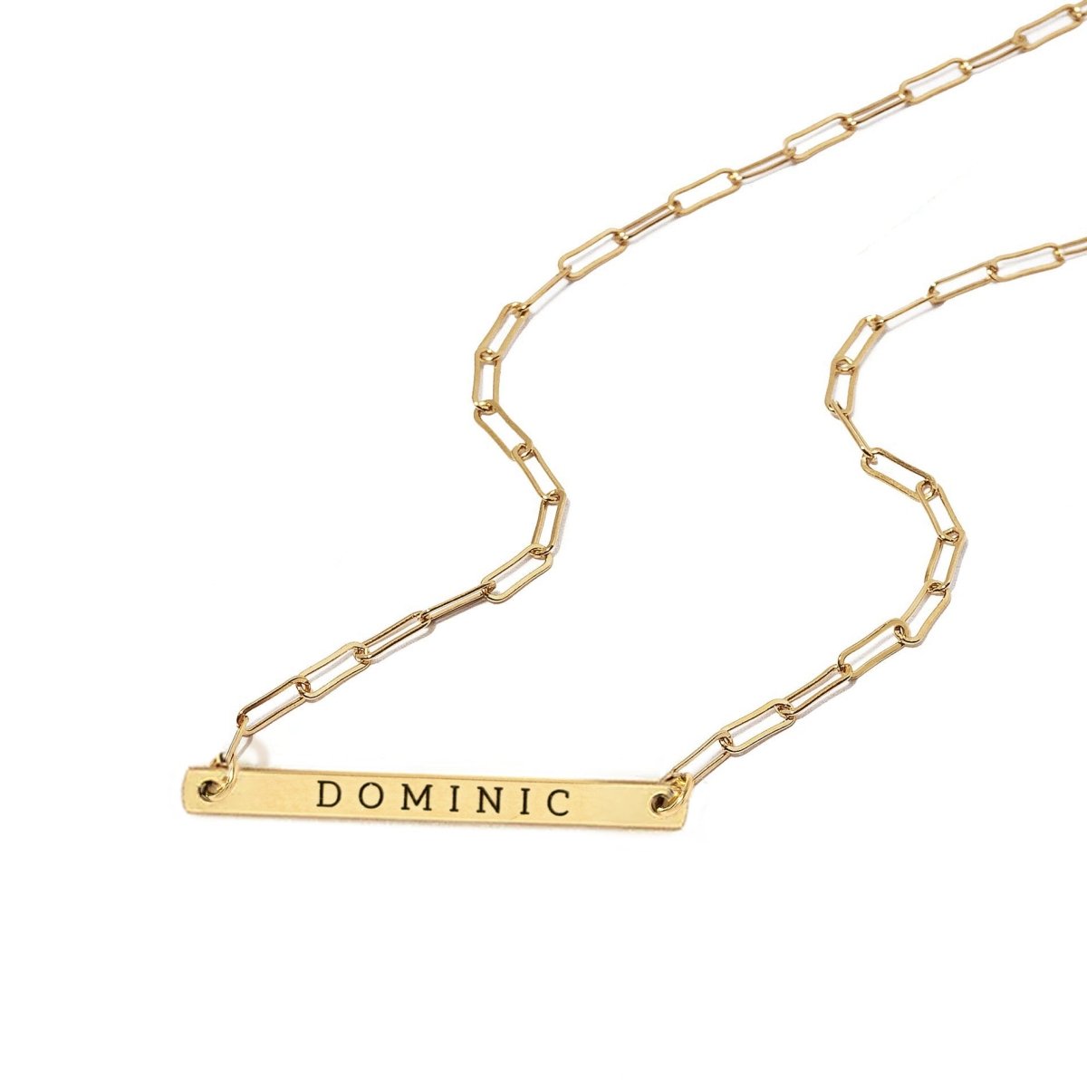 Gold-filled paperclip chain necklace with a thin bar pendant engraved with a name, on a white background