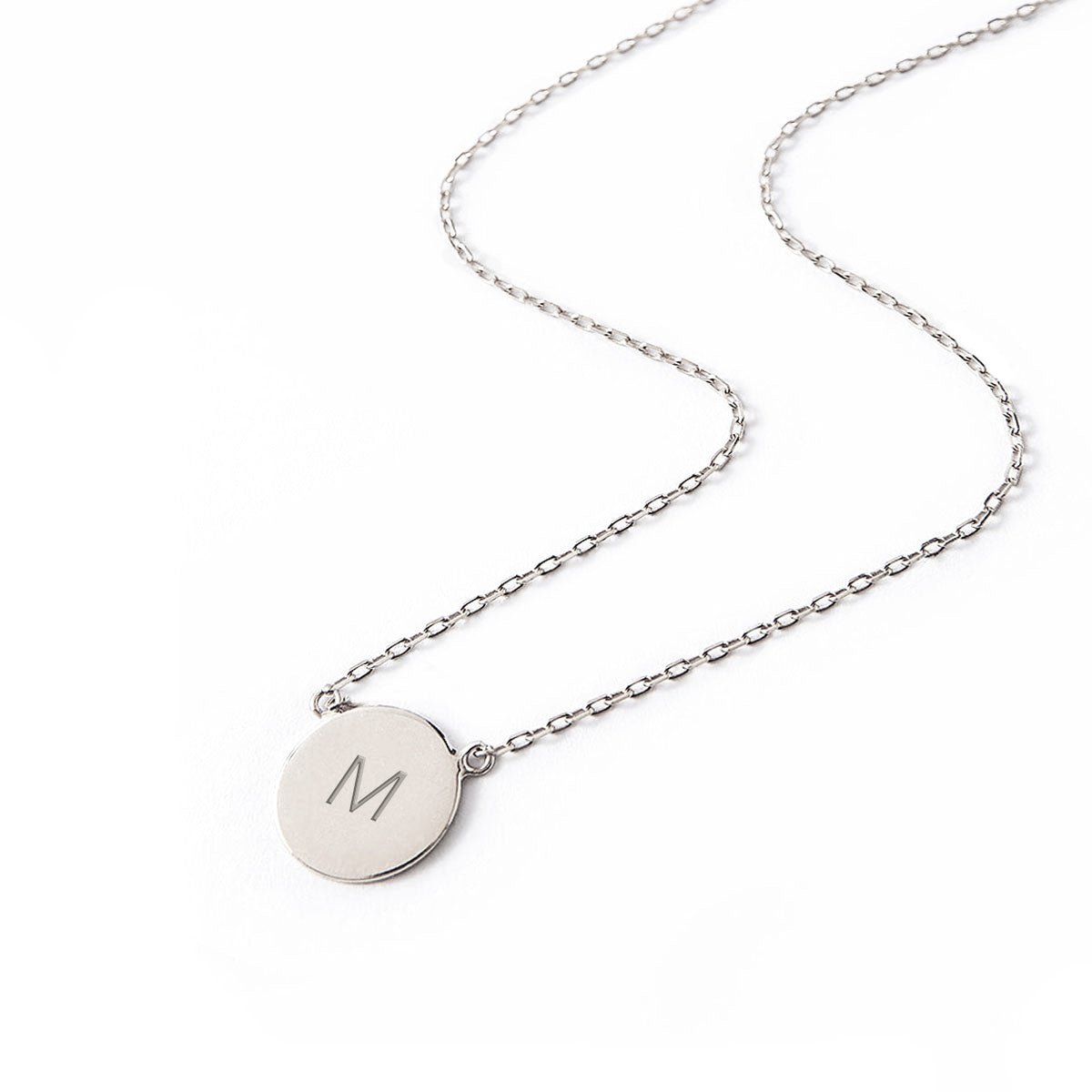 Sterling silver initial disc necklace on a fine chain, engraved with an initial, on a white background