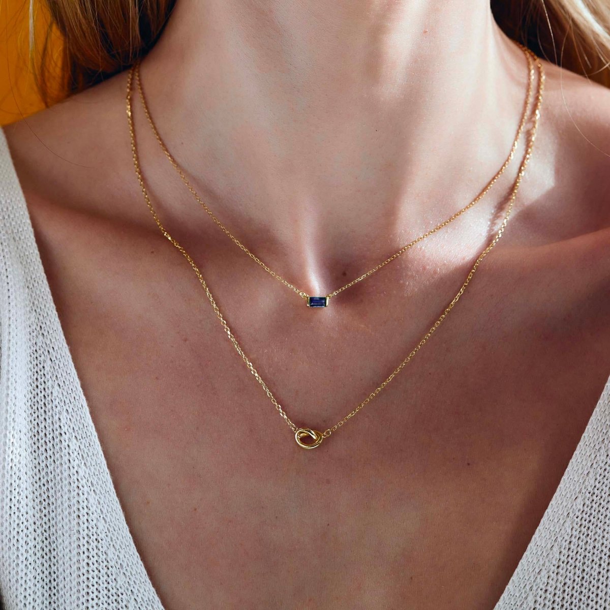 Gold vermeil layered duo with a blue baguette pendant and a knot chain, shown on a model's neckline