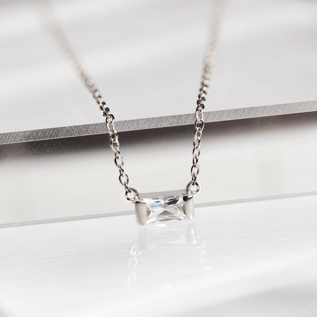 Sterling silver baguette necklace with a clear white zirconia pendant, close-up detail