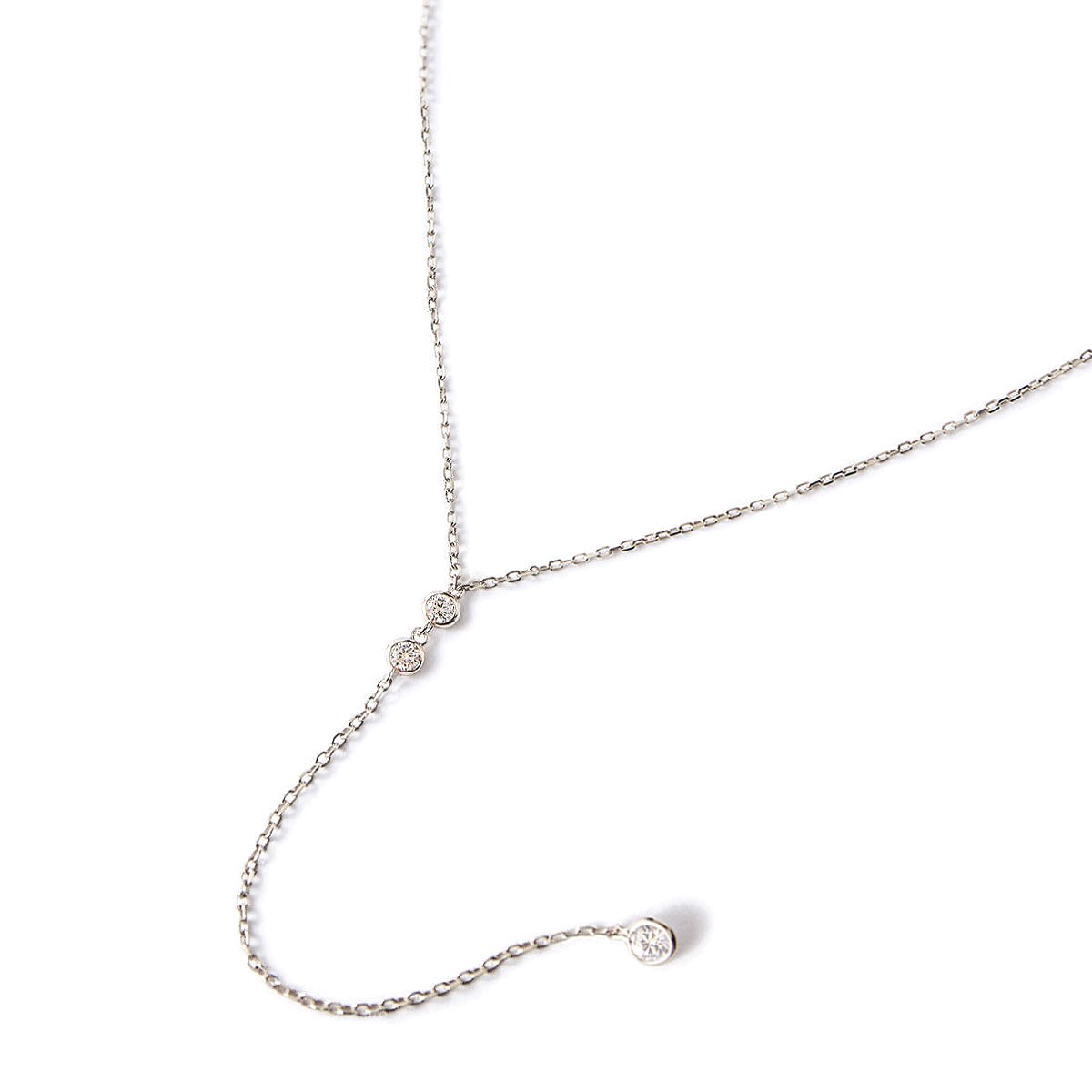 Sterling silver lariat necklace with two zirconia bezels and a drop stone, on a white background