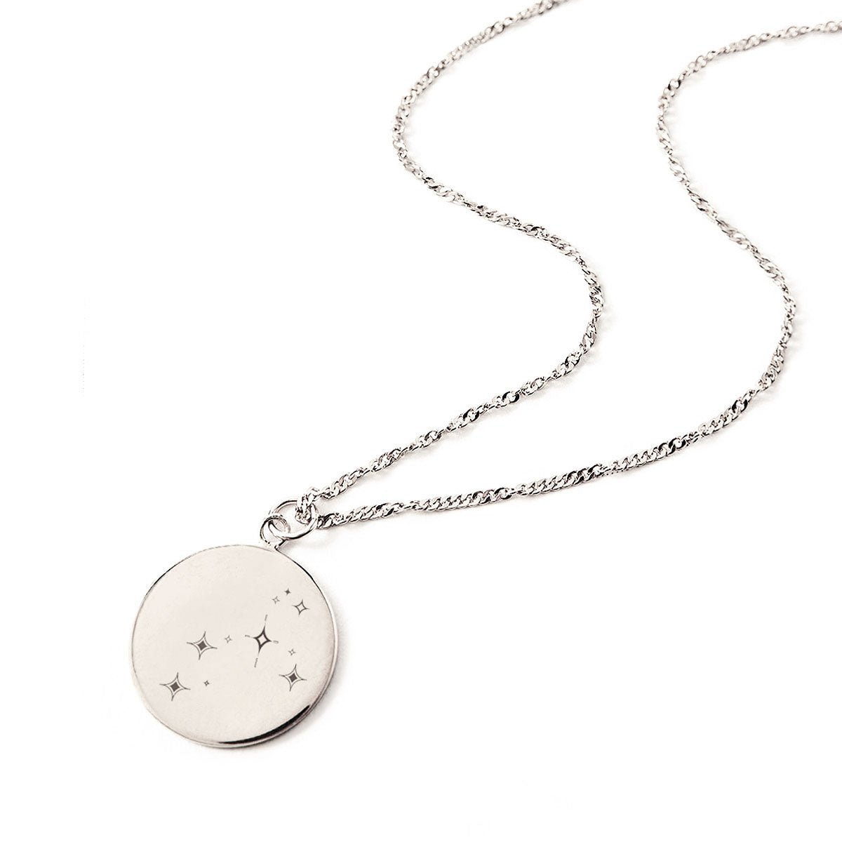 Sterling silver round disc necklace engraved with a star constellation, laid on a white background