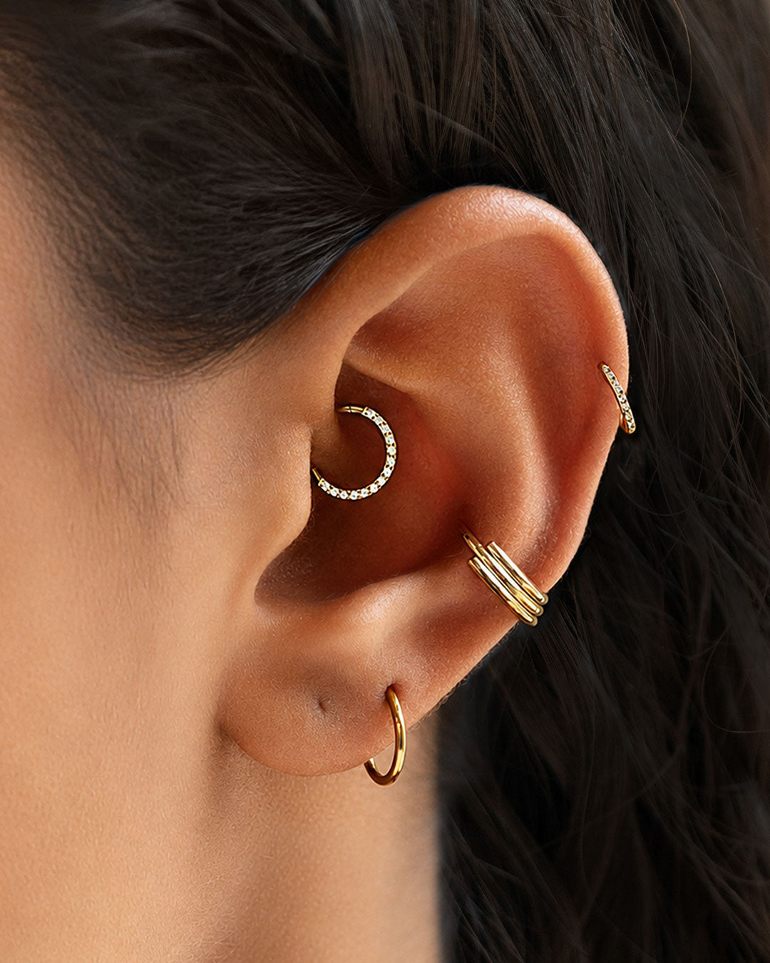 Ear stack with a gold crystal daith hoop, triple-band conch cuff, helix hoop and plain lobe hoop