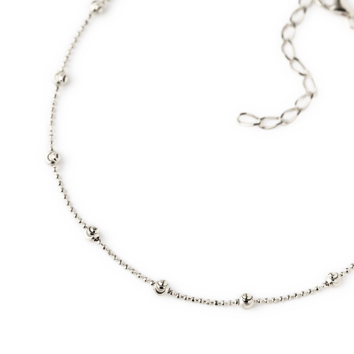 Sterling silver faceted beaded anklet close-up showing beaded stations and chain extender, on a white background
