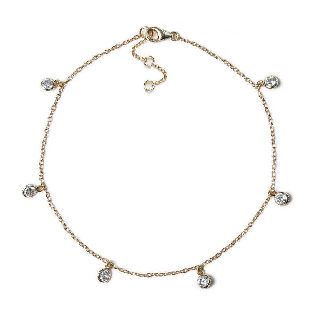 Gold vermeil anklet with six dangling round bezel-set clear stones, on a white background