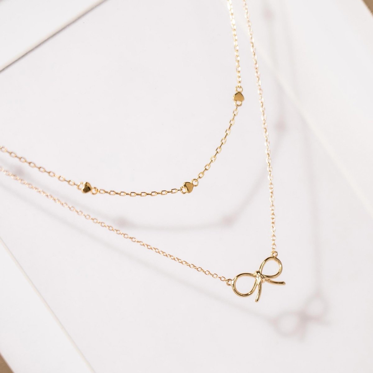 Gold vermeil heart-station chain necklace shown layered with a gold heart pendant, on a white background