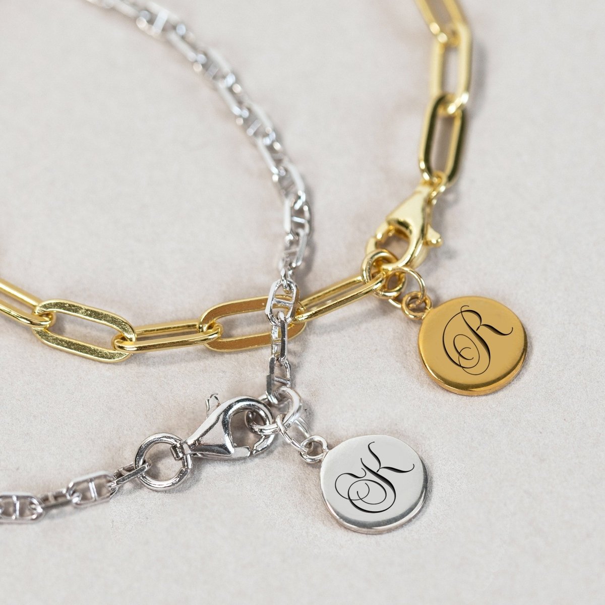Gold and silver Marina chain bracelets with engraved initial charms, shown close-up