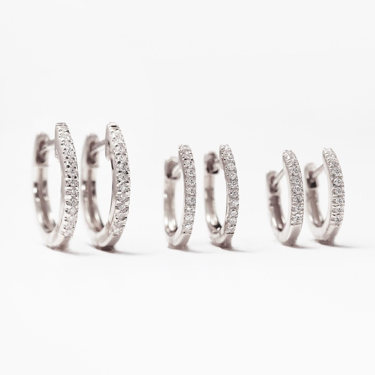 14K white gold pavé diamond huggie hoops shown in three sizes, on a white background