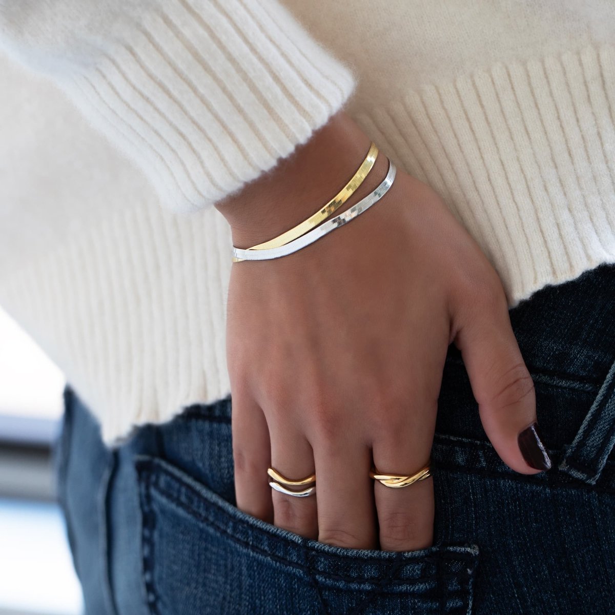 Gold vermeil and silver herringbone chain bracelets layered together, shown on a model's wrist