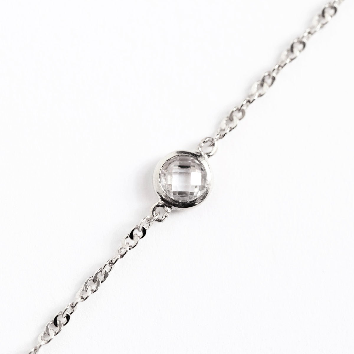 Sterling silver Singapore chain bracelet, close-up detail of the round faceted clear bezel stone