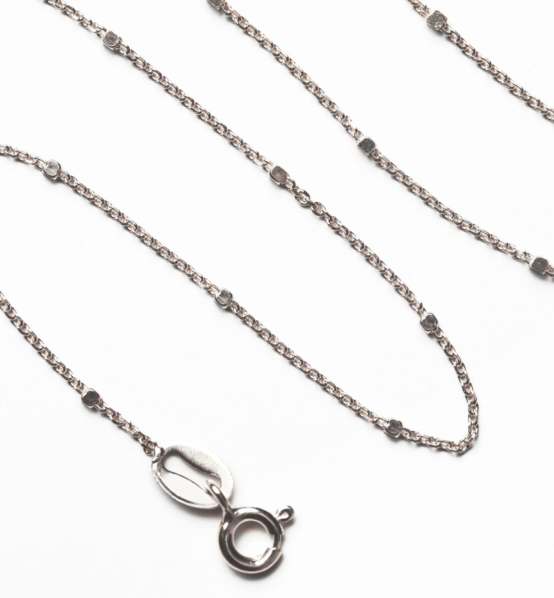 Sterling silver dainty satellite bead chain with spring-ring clasp, close-up detail on a white background