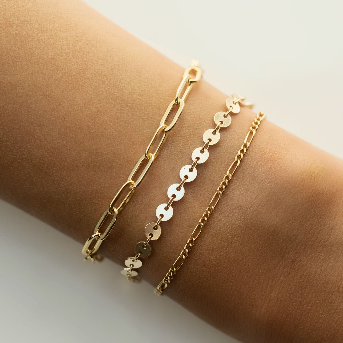 Gold vermeil Figaro chain bracelet stacked with two chain bracelets, shown on a model's wrist