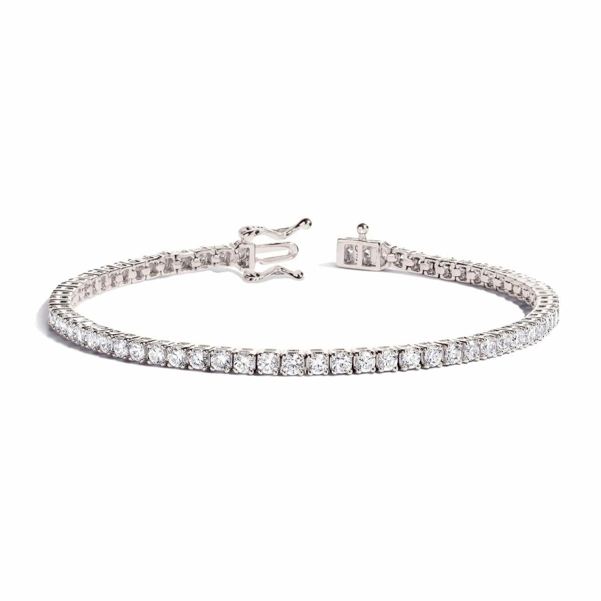 Sterling silver tennis bracelet with round white zirconia and a box clasp, laid open on a white background