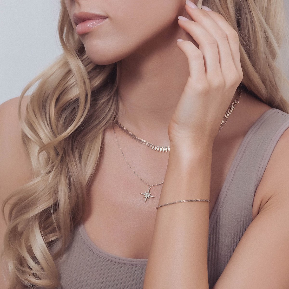 Sterling silver Figaro chain bracelet shown on a model's neckline and wrist with layered chains