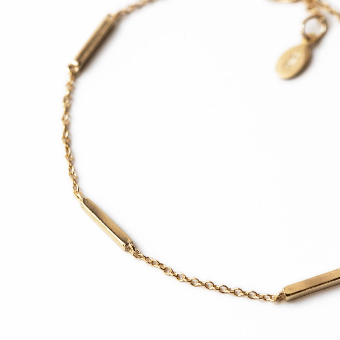 Gold vermeil bar station bracelet, close-up detail of the bars and thin chain on a white background