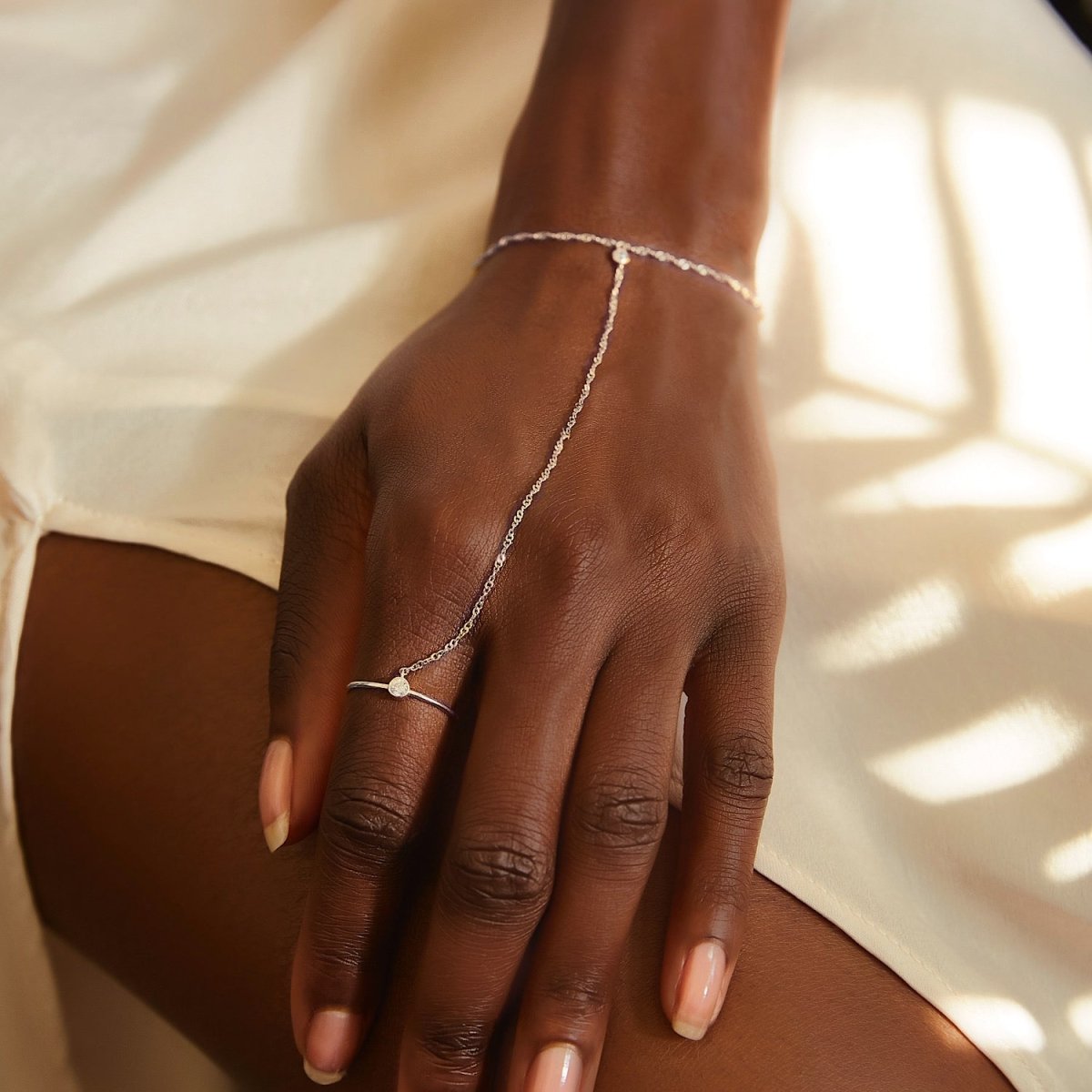 Sterling silver handchain with a bezel-set clear stone, shown draped across a model's hand