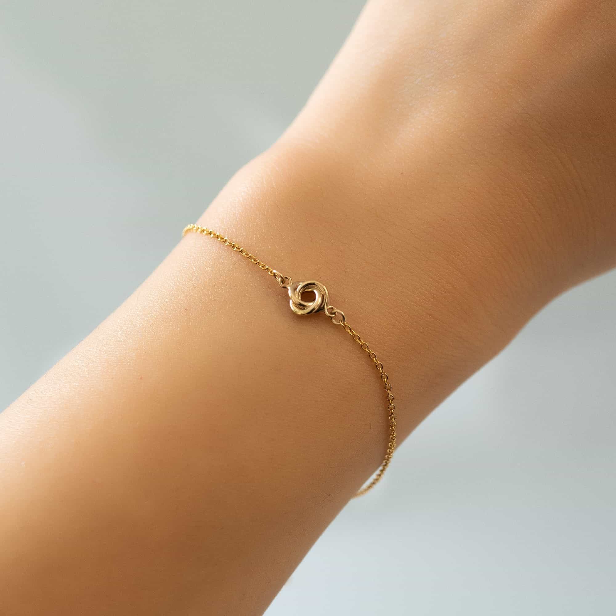 Gold-filled love knot chain bracelet with a small knot bead shown on a model's wrist
