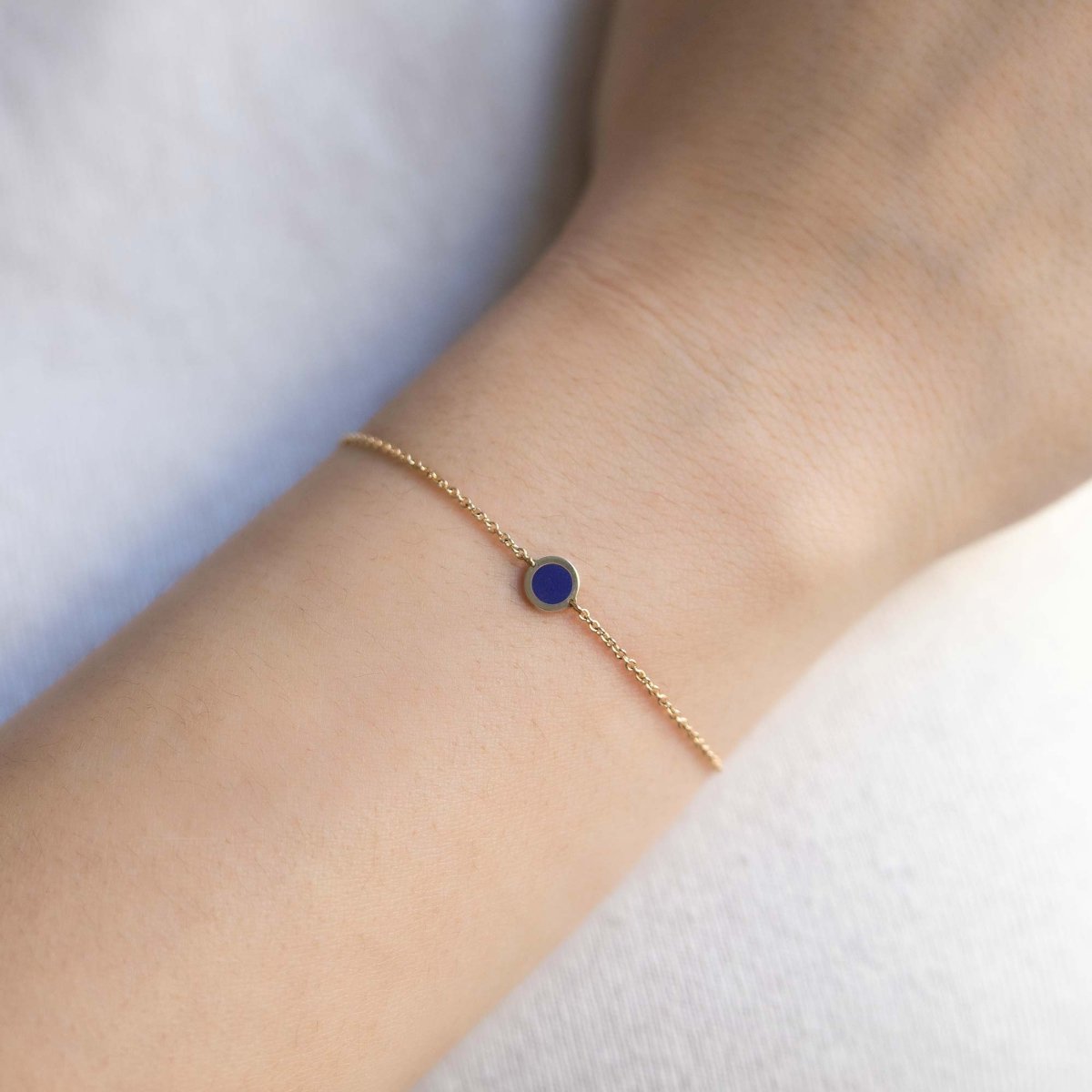 14K gold chain bracelet with a round lapis lazuli disc, shown on a model's wrist