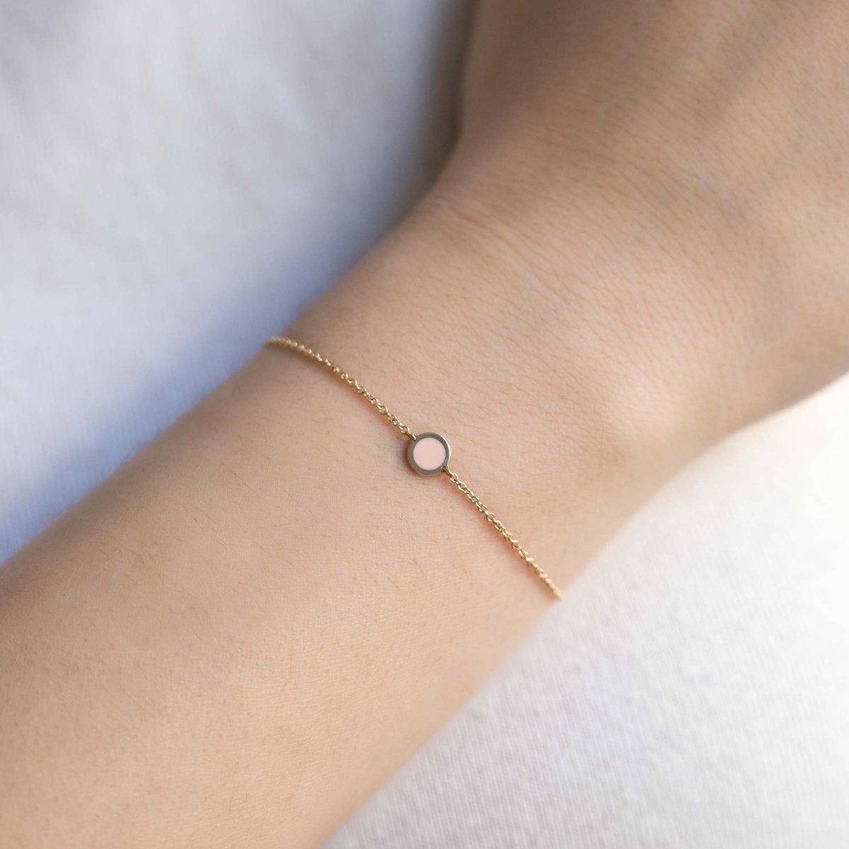 14K gold chain bracelet with a single round pink rose quartz stone, shown on a model's wrist